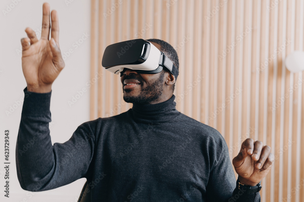 Smiling African American businessman in VR glasses, office setting, testing virtual reality goggles, impressed with 3D technology, interacting with virtual objects. Smiling African American businessman in VR glasses, office setting, testing virtual reality goggles, impressed with 3D technology, interacting with virtual objects.