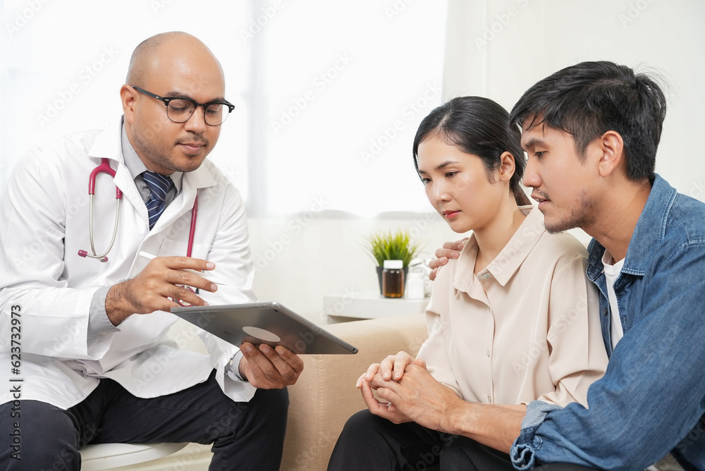 Male doctor giving test result to asian couple patient with tablet. They feeling stressed after received bad news from the doctor in medical office, hospital, clinic or home. Male doctor giving test result to asian couple patient with tablet. They feeling stressed after received bad news from the doctor in medical office, hospital, clinic or home.