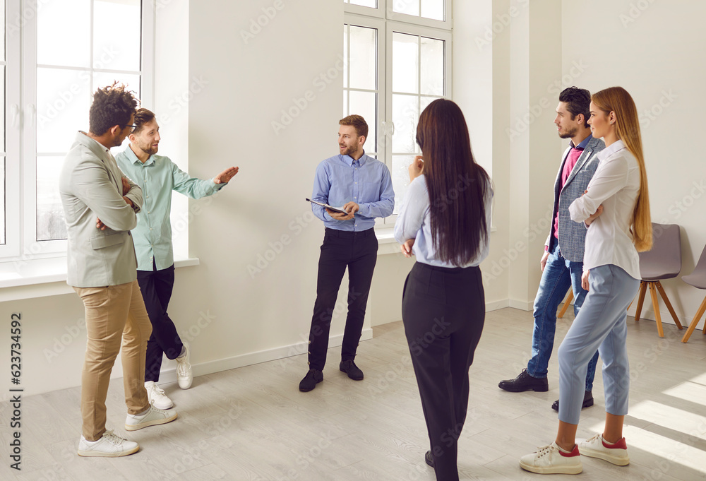 Business team having a discussion during a work meeting. Group of young diverse mixed race people standing in the office, talking, listening to each other, and making suggestions
