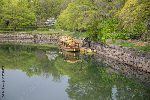 A small beautiful  yellow boat mooring near the big trees.