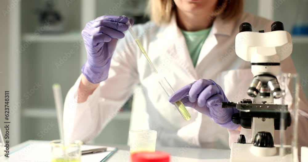 Drop of oil or urine drips from pipette into test tube in laboratory