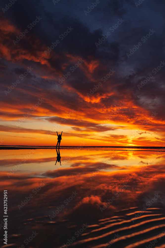 silhouette person against background beautiful sunset sky on ocean, reflection rays sun and sky in water. Freedom inspiration in nature under open sky enjoys beautiful view and meditates, happiness