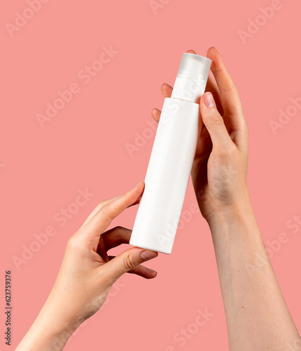 Hand holding spray bottle mockup, blank beauty product on pink background