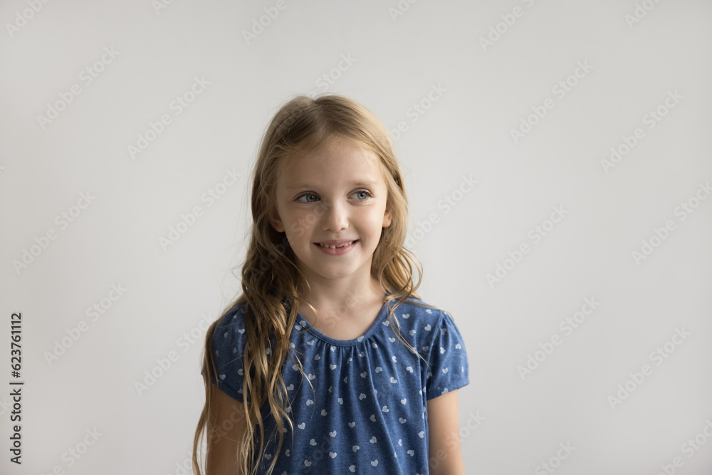 Positive pretty cute little girl posing at white wall background, smiling, looking away. Beautiful preschool model kid with long fair hair and tooth gaps wearing blue casual t-shirt portrait Positive pretty cute little girl posing at white wall background, smiling, looking away. Beautiful preschool model kid with long fair hair and tooth gaps wearing blue casual t-shirt portrait