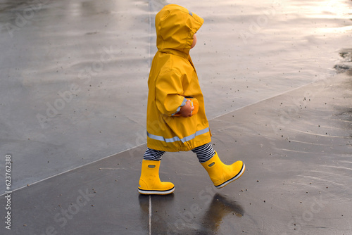 A small child going through puddles on a rainy day.