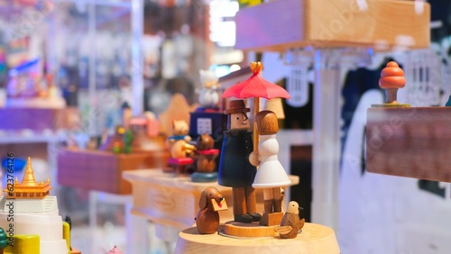 Wooden music box is spinning in a display case. Close up wooden people under an umbrella are spinning on a music box. Concept buy a music box with wooden people for a child and make him happy.