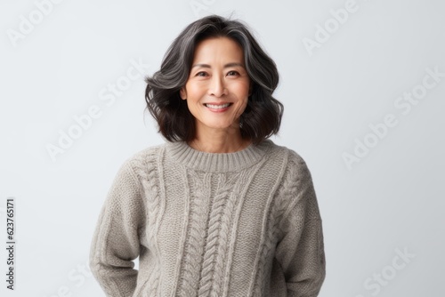 Portrait of a smiling asian woman in sweater standing against white background