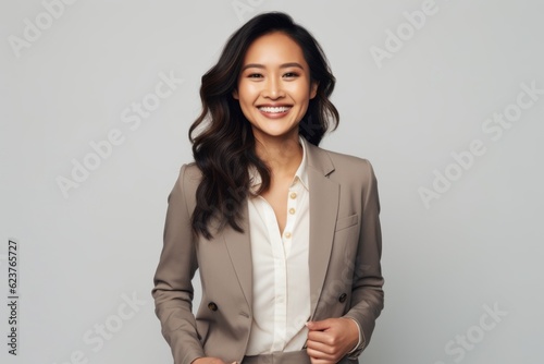 Portrait photography of a satisfied Indonesian woman in her 30s wearing a classic blazer against a white background 
