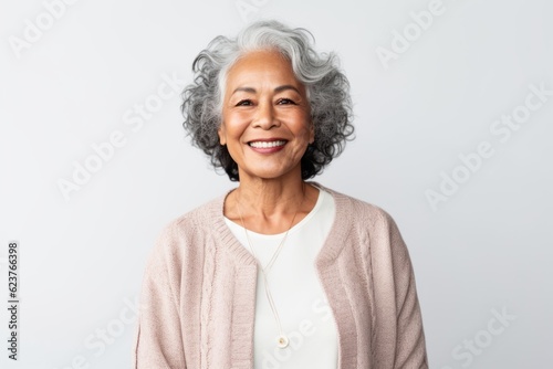 Portrait photography of a pleased Indonesian woman in her 60s wearing a chic cardigan against a white background 