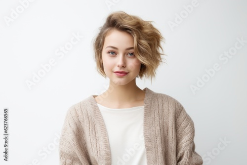 Portrait of attractive european female with blond hair, wearing beige sweater, posing over white background.