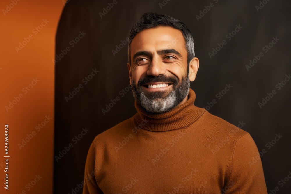 Obraz premium smiling indian man in brown sweater looking at camera isolated on black
