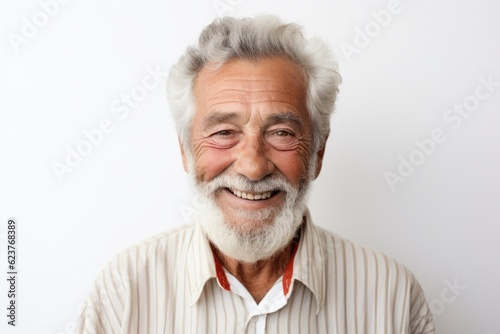 Portrait of happy senior man smiling at camera while standing against white background © Robert MEYNER