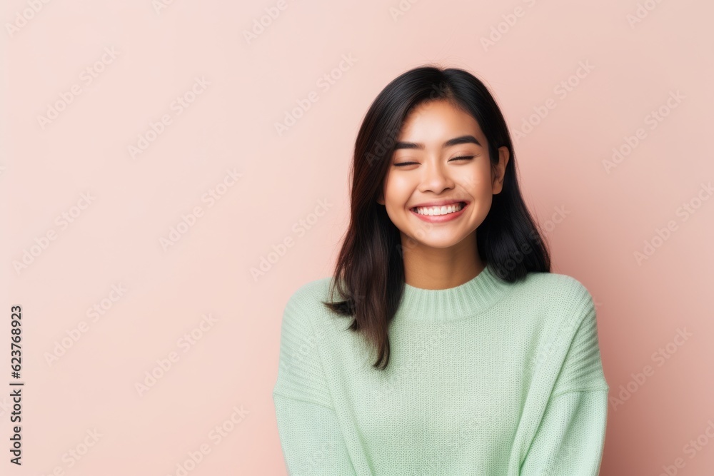 Portrait of a smiling asian woman in green sweater on pink background Portrait of a smiling asian woman in green sweater on pink background