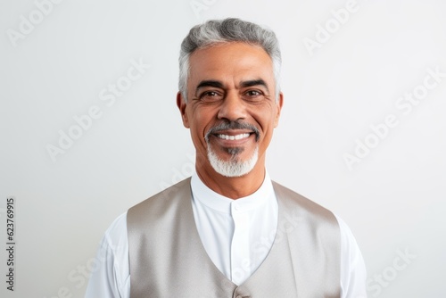 Portrait of mature Indian man smiling at camera while standing against white background