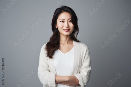 Portrait of a beautiful asian woman in white sweater on grey background