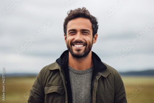 Close up portrait of handsome young man smiling at the camera while standing outdoors