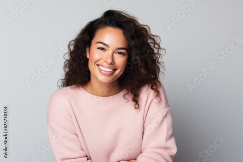 Portrait of a smiling young woman with curly hair over gray background