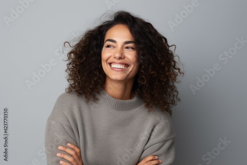 Portrait of a smiling young woman with curly hair isolated on gray background