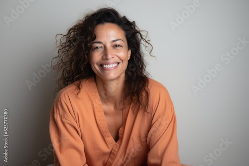 Portrait of a beautiful young woman with long curly hair in an orange shirt