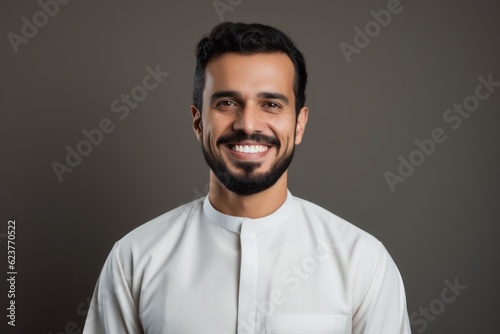 portrait of smiling bearded indian man in white shirt isolated on grey