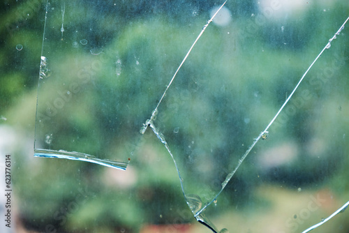 Broken window glass in the house, on a green background. Glass fragments, cracks