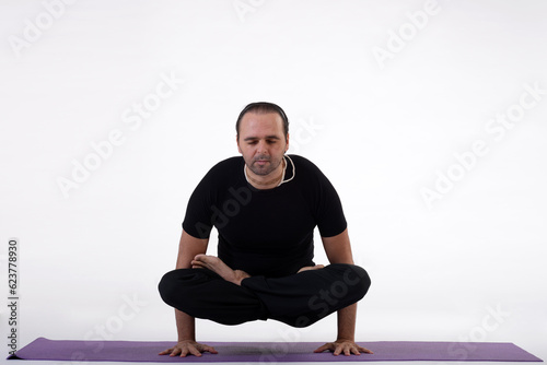 Man doing yoga in photo studio on isolated white background. © AkosHorvathWorks