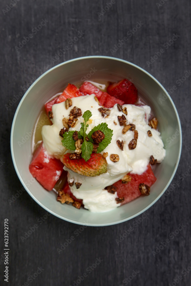 Greek yoghurt in a bowl with fruit slices and honey