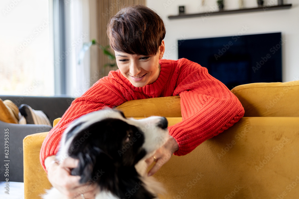 © leszekglasner - Happy woman on couch stroking her border collie dog