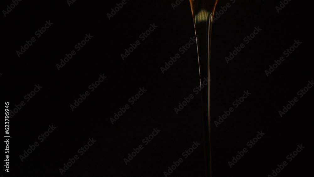 Closeup thick liquid drop of honey falling over black background. Closeup thick liquid drop of honey falling over black background.