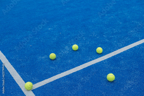 selective focus , centre line of a blue paddle tennis court with five balls © Vic