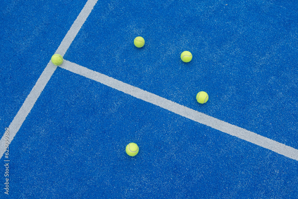 five balls on a blue paddle tennis court