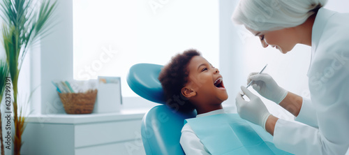 An African-American child sitting in a dental clinic chair with their mouth open, waiting for the dentist to perform an oral inspection