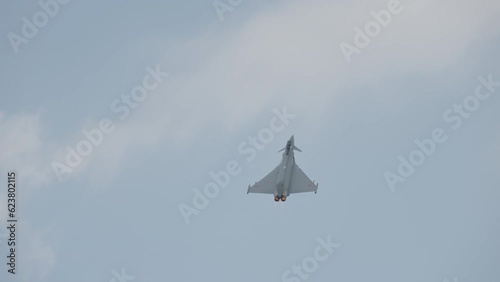 Fast fighter jet during high speed combat maneuvers with clouds