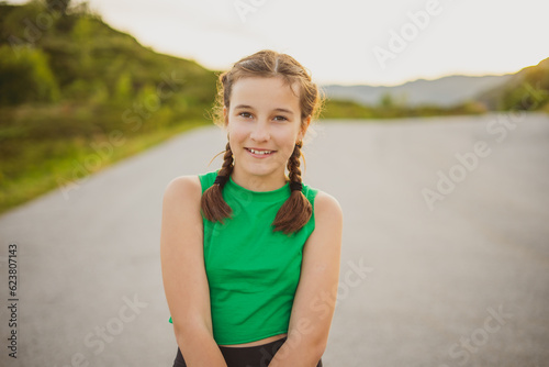 Outdoor portrait of cute little girl with two pigtails against backdrop of mountains and nature