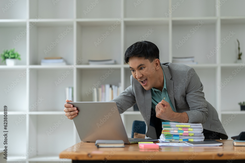 confident young businessman Happy smart gesture excited with laptop computer and raised arms to celebrate happy financial business success startup business ideas. confident young businessman Happy smart gesture excited with laptop computer and raised arms to celebrate happy financial business success startup business ideas.