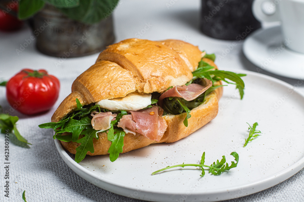 Croissant with jamon, mozzarella and arugula on a plate