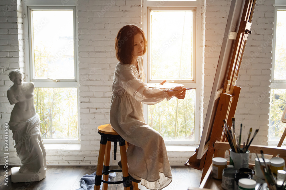Young female painter painting in a studio Young female painter painting in a studio