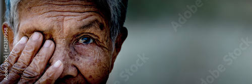 Old women cover her eye with her hand for eye testing in panoramic view use for medical and healthcare background	 photo