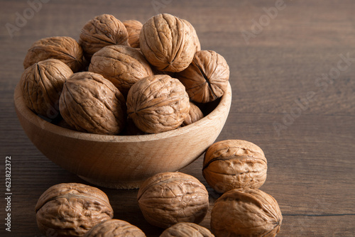 Whole walnuts in shell in bowl on wooden table