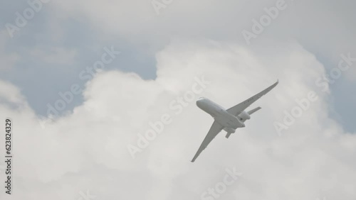 Large white private business Jet during flight under blue sky with clouds