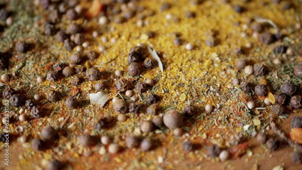 Dried Spices Falls on a Rotating Wooden Background of Colorful Spices. Close up. Slow motion. Scattered Indian spice mix, black peppercorns, turmeric, paprika, coriander, oregano. Background, texture. Dried Spices Falls on a Rotating Wooden Background of Colorful Spices. Close up. Slow motion. Scattered Indian spice mix, black peppercorns, turmeric, paprika, coriander, oregano. Background, texture.