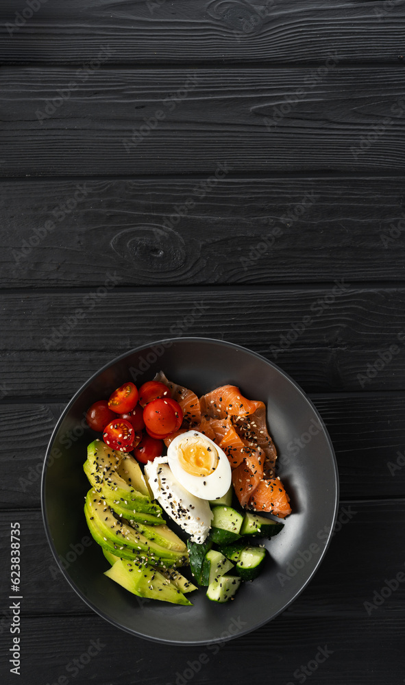 Low-carbohydrate breakfast concept. Salmon salad for ketogenic diet with avocado, cucumber, tomato and sesame on wooden background. top view. Banner.