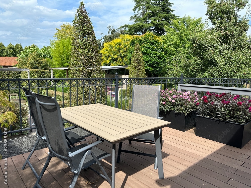 Balcony with flowers. Balcony terrace with garden table, chairs and Dahlia pinnata in black stylish planters. Wooden decking