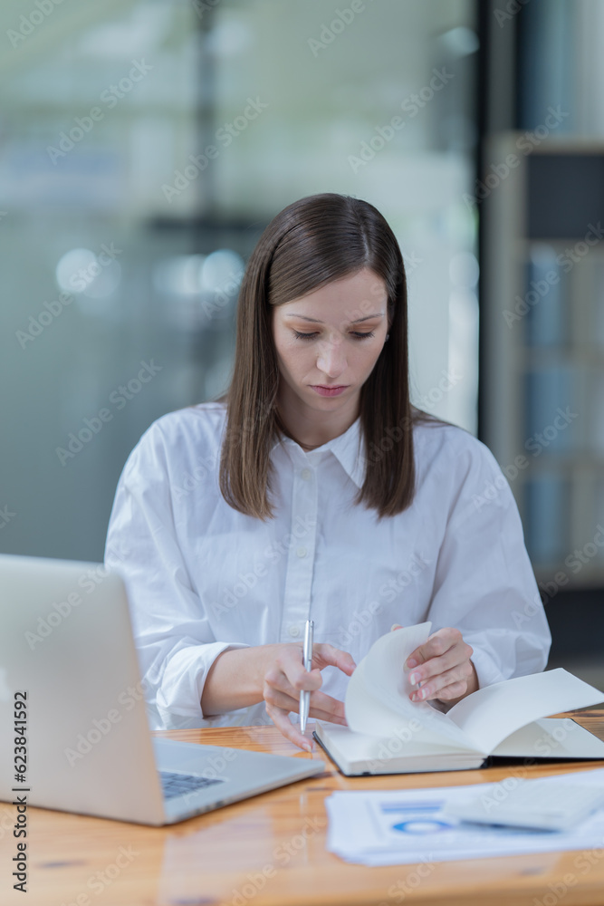 Portrait of beautiful smiling young brunette businesswoman sitting at in the office modern work station