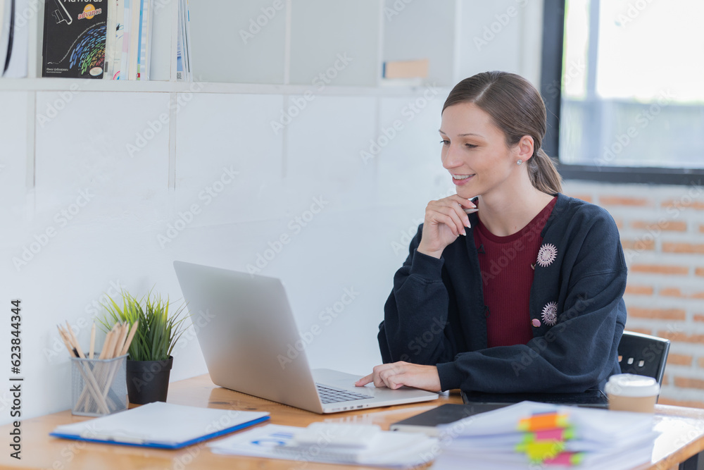Attractive young office worker holding a binder as she looks at the camera with a sweet friendly smile Attractive young office worker holding a binder as she looks at the camera with a sweet friendly smile