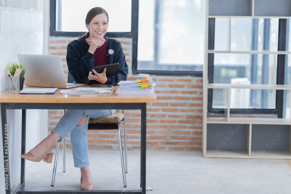 Attractive young office worker holding a binder as she looks at the camera with a sweet friendly smile Attractive young office worker holding a binder as she looks at the camera with a sweet friendly smile