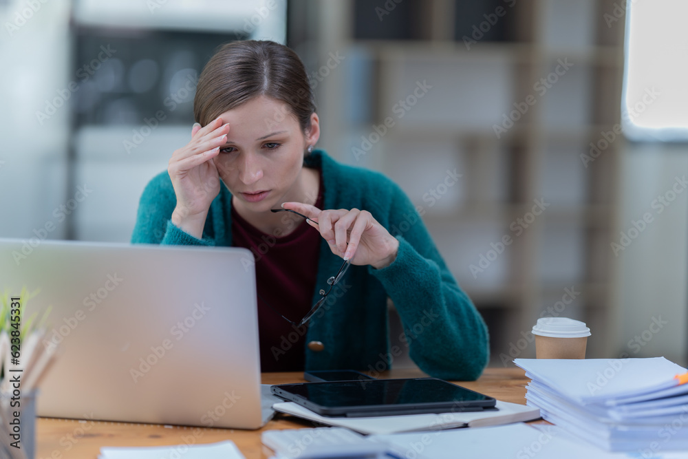 Fototapeta premium Portrait of American businesswoman celebrating success with arms raised in front of a laptop in the office,