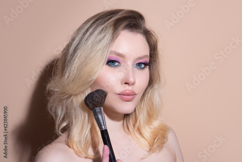 Beautiful young woman with makeup blusher brush. Facial treatment. Cosmetology, beauty and spa. Portrait of beauty model with make up on beauty face.