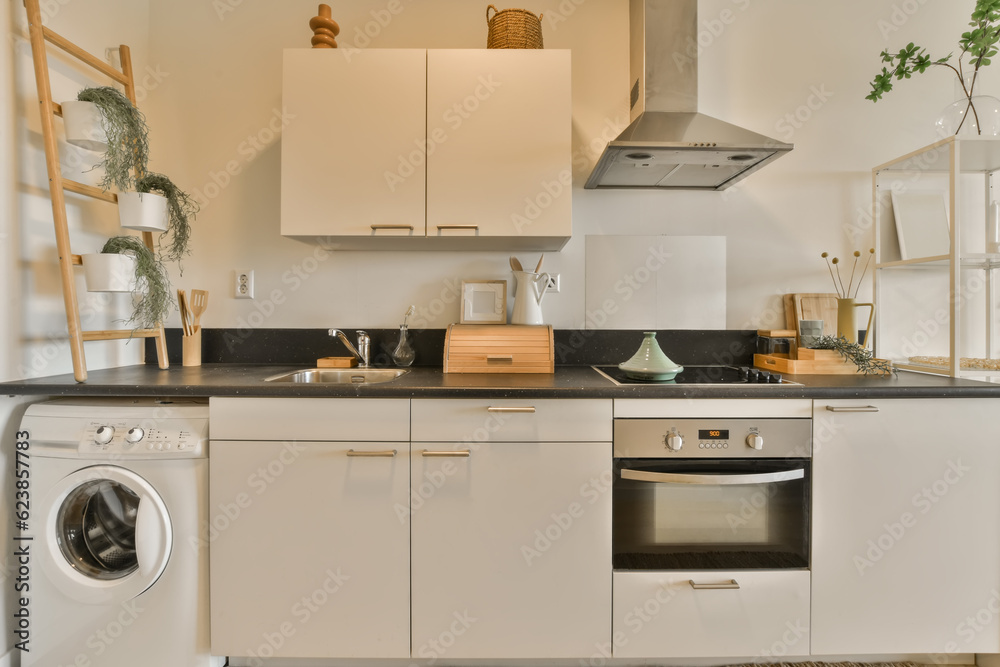 Fototapeta premium a kitchen with white cabinets and black counter tops, including a washing machine in the middle part of the room