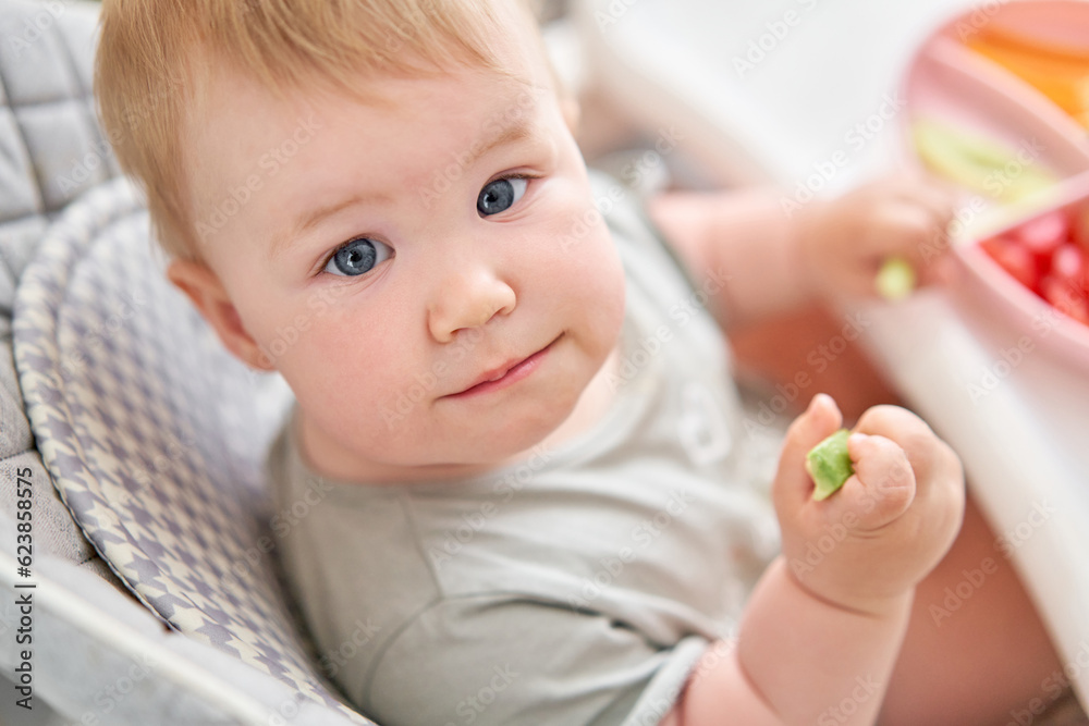 Cute child eats healthy food pasta and vegetables steamed,. Portraits of a cute 10 months old baby girl. The baby sitting in a special high chair for babies. Cute child eats healthy food pasta and vegetables steamed,. Portraits of a cute 10 months old baby girl. The baby sitting in a special high chair for babies.